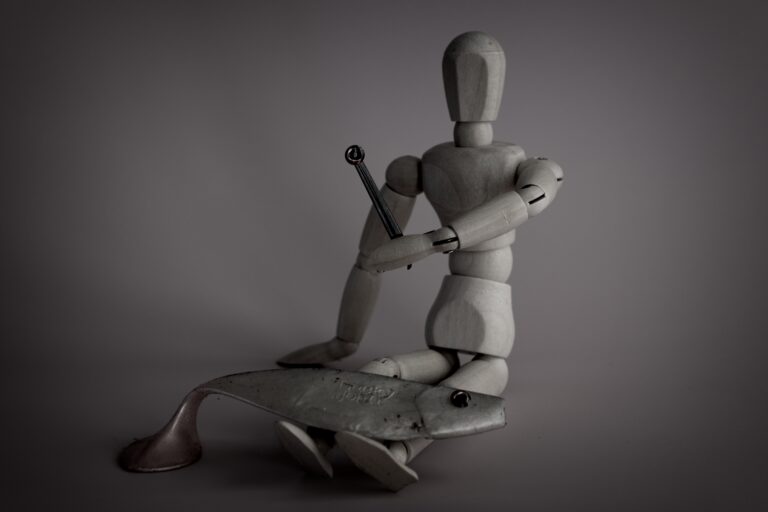 Wooden figure sitting still, holding a fish and raising a silver eye between chopsticks. Calm, eerie, and ritualistic.